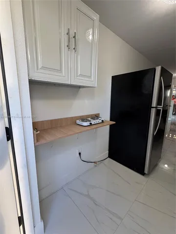 a view of a refrigerator in kitchen and an empty room