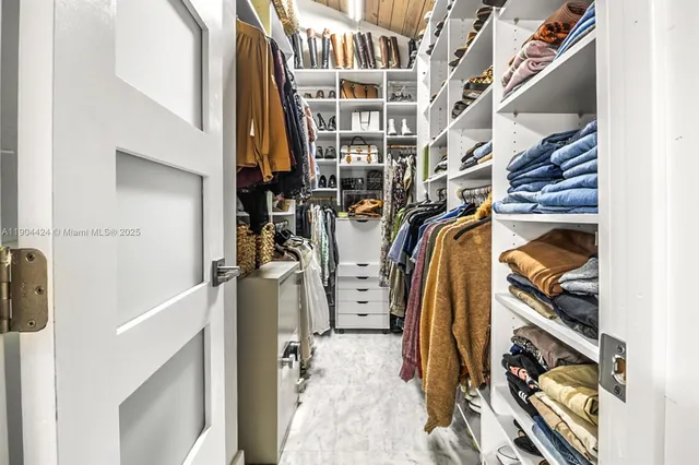 a view of walk in closet with clothes and shoes