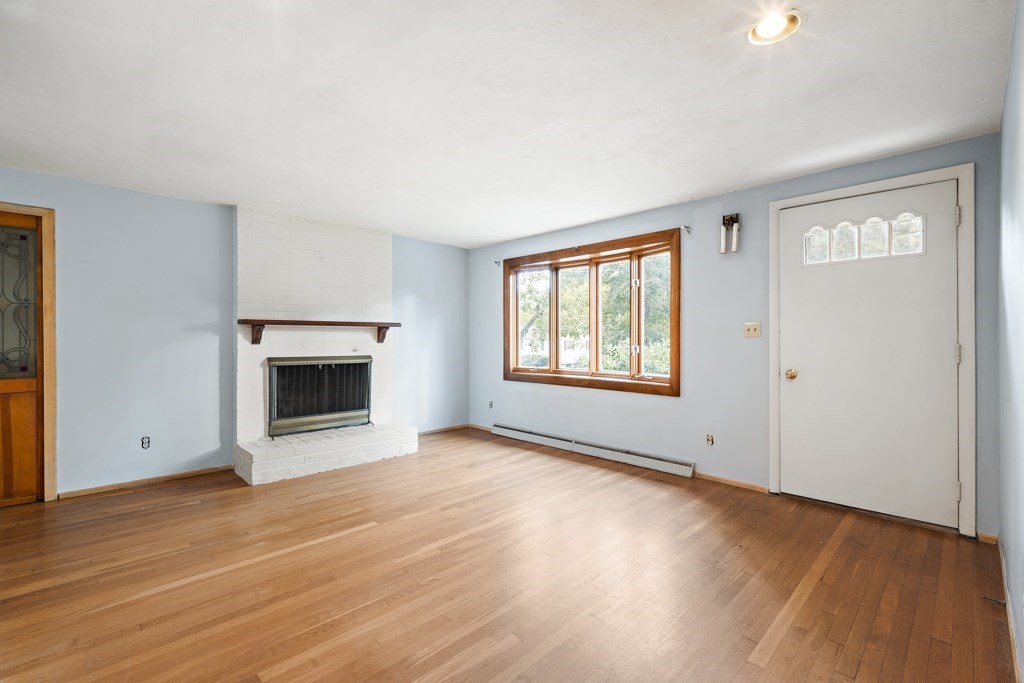 53 Cochato Park Randolph, MA 02368 - Photo 6 of 20 an empty room with wooden floor a fireplace and windows