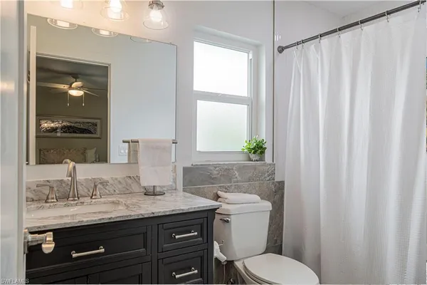 a bathroom with a granite countertop sink toilet and mirror