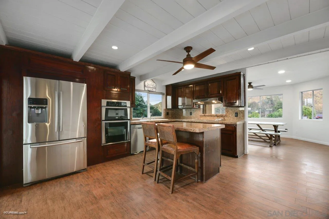 2925 Cordrey Drive Escondido, CA 92029 - Photo 12 of 75 a kitchen with stainless steel appliances kitchen island granite countertop a refrigerator a stove a sink a dining table and chairs with wooden floor