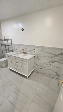 a bathroom with a granite countertop sink a toilet and shower