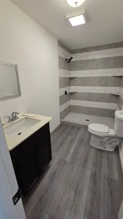 a bathroom with a toilet and a wooden floor