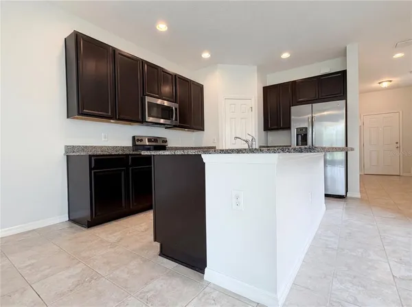 a kitchen with stainless steel appliances granite countertop a stove top oven a sink and a refrigerator
