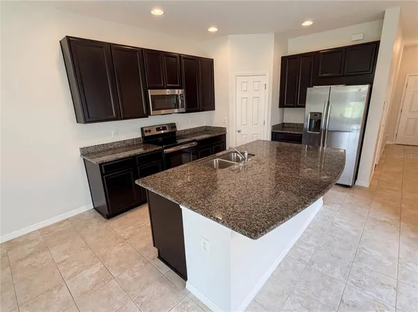 a kitchen with stainless steel appliances granite countertop a sink a microwave a refrigerator and a stove
