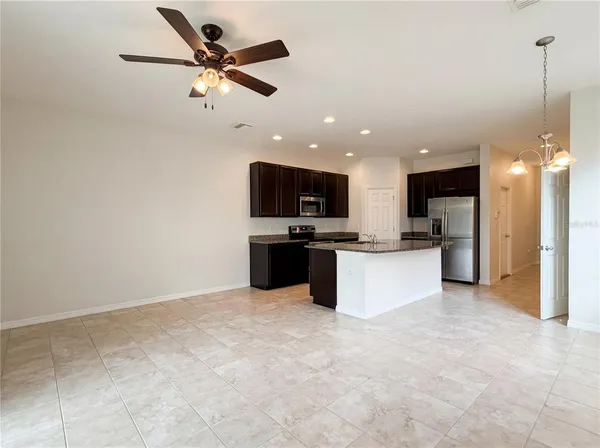 a view of kitchen with kitchen island stainless steel appliances refrigerator stove microwave and cabinets