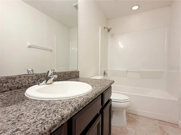a bathroom with a granite countertop sink a toilet a mirror and bathtub