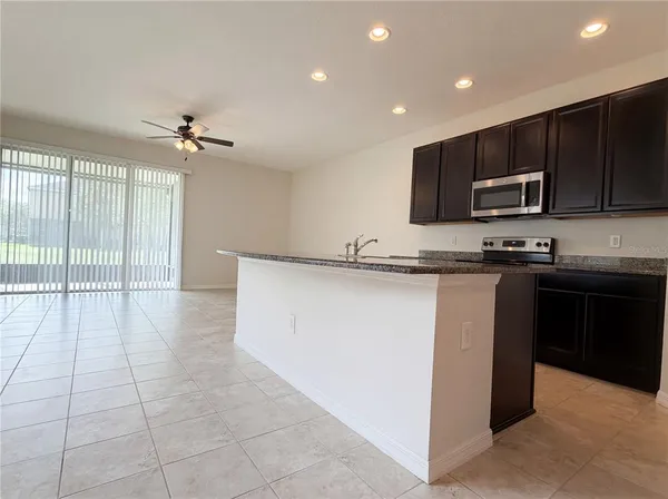 a kitchen with kitchen island granite countertop a stove a sink and a microwave