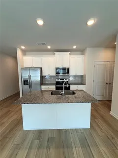 a large kitchen with granite countertop a large counter top stainless steel appliances and cabinets