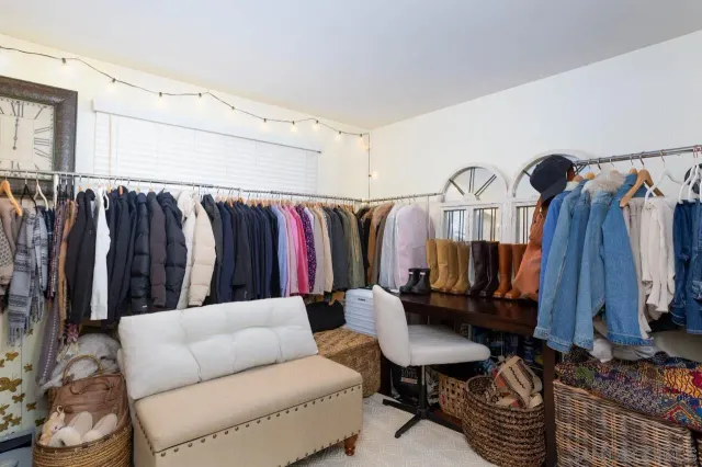 a walk in closet with clothes and shoes