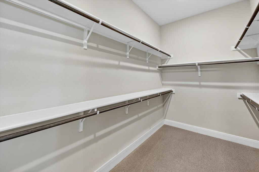 2237 Pika Road Northlake, TX 76247 - Photo 21 of 37 Walk-in closet featuring light beige wall paint, white shelving, dark wood-finish hanging rods, and light brown carpeting