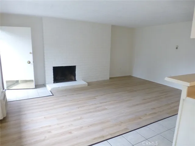 an empty room with wooden floor fireplace and windows
