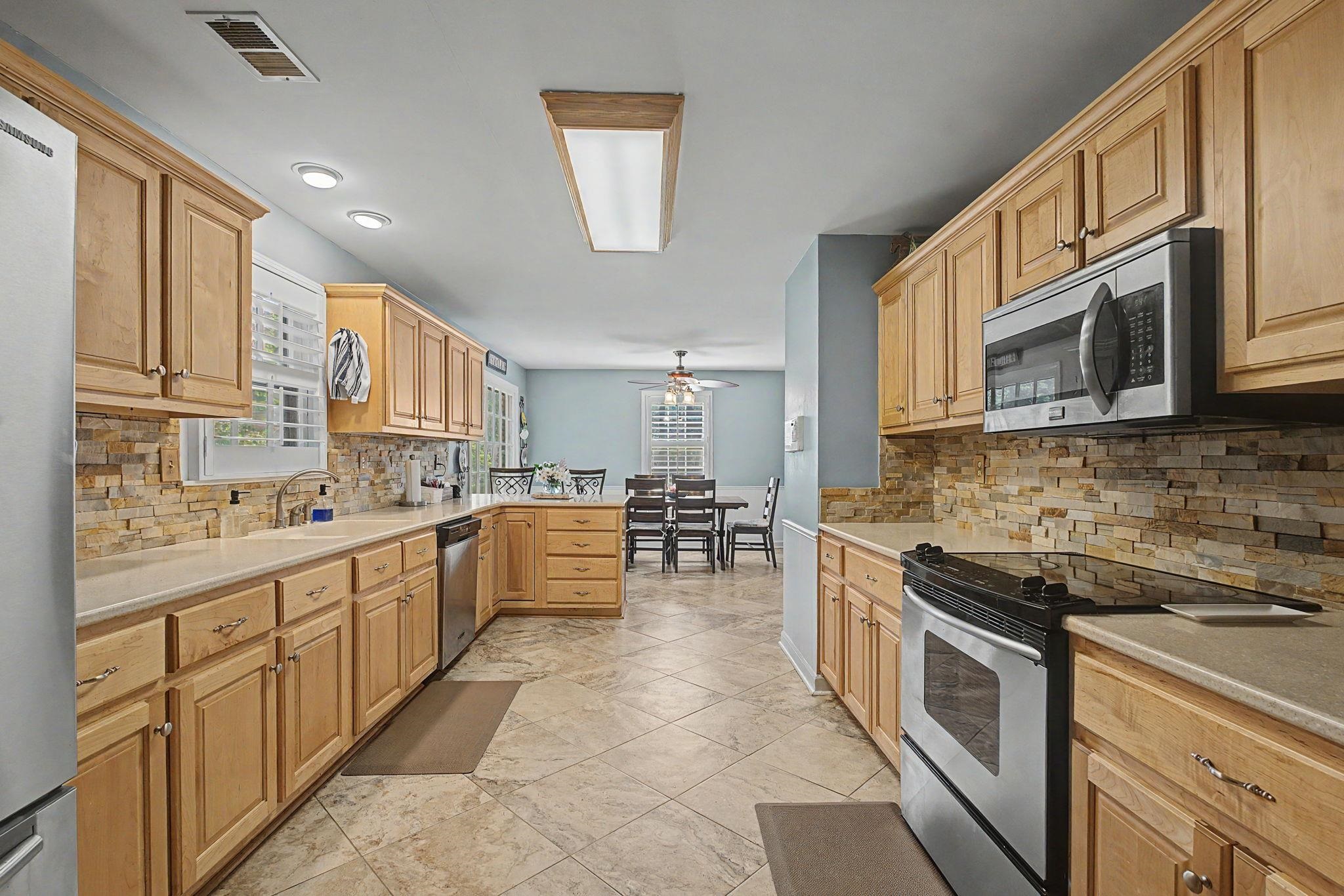 1929 Miller Farms Road Germantown, TN 38138 - Photo 15 of 40 Spacious kitchen featuring light wood cabinetry, stainless steel appliances, stacked stone backsplash, and tile flooring