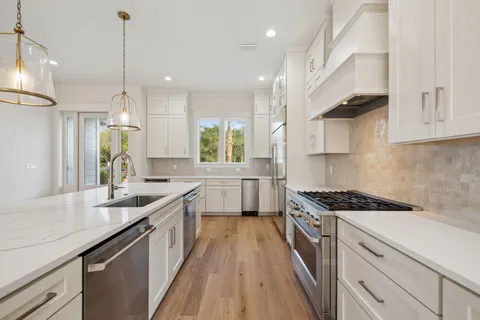 a kitchen with kitchen island stainless steel appliances a sink a stove a counter space and a window