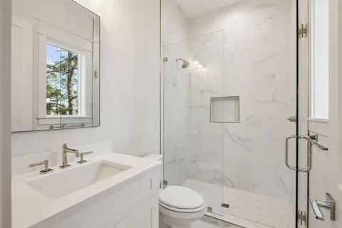 a bathroom with double vanity sink a two mirror a window a bathtub and vanity