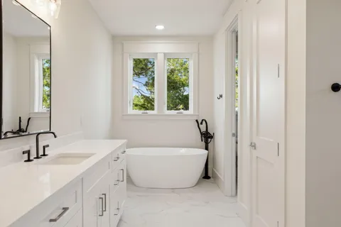 a view of a white house next to a yard with plants and trees