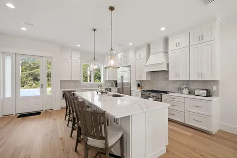 a kitchen with stainless steel appliances granite countertop a stove a refrigerator a kitchen island a stove and a wooden floors