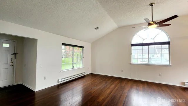 a view of a room with wooden floor chandelier and windows