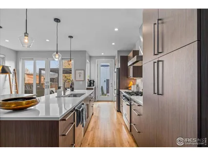 a kitchen with stainless steel appliances granite countertop a refrigerator a sink dishwasher a stove and white cabinets with wooden floor