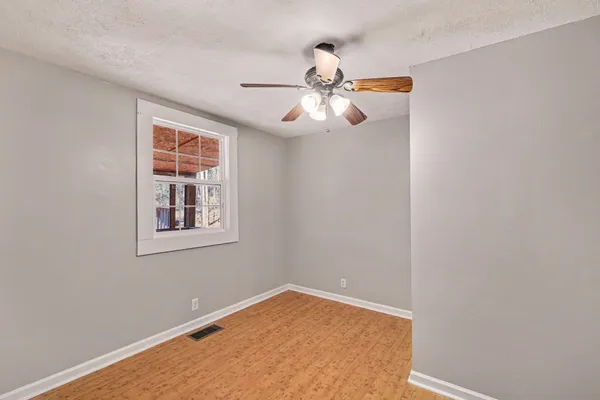 an empty room with windows and fan