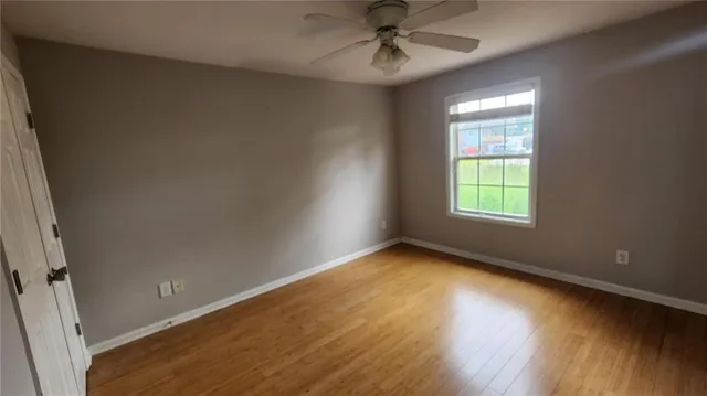 an empty room with wooden floor fan and windows