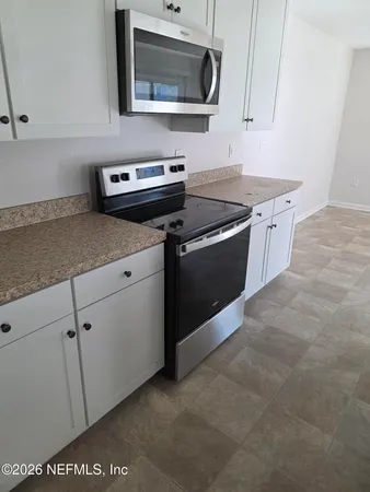 a kitchen with stainless steel appliances granite countertop a sink a stove a microwave oven with cabinets and wooden floor