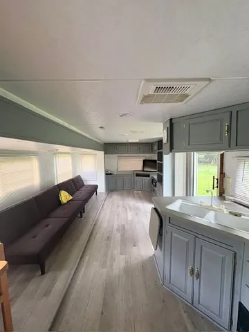 a living room with stainless steel appliances furniture a rug and a view of kitchen