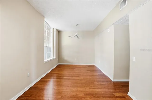 a view of an empty room with wooden floor and a window