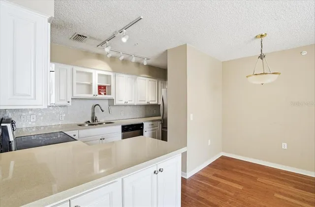 a kitchen with granite countertop a sink cabinets and stainless steel appliances