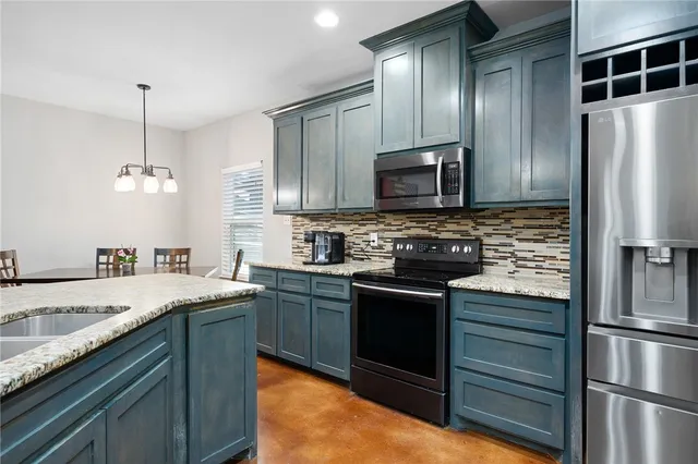 a kitchen with kitchen island granite countertop stainless steel appliances and refrigerator