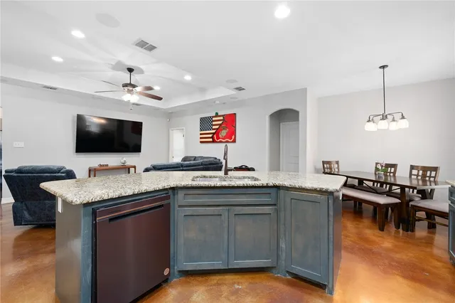 a kitchen with a stove a sink and a flat screen tv