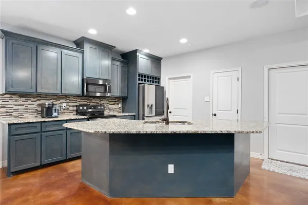 a kitchen with kitchen island stainless steel appliances a sink stove refrigerator and cabinets