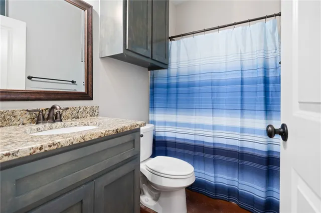 a bathroom with a granite countertop toilet sink and mirror