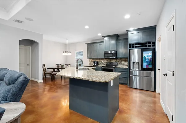 a kitchen with stainless steel appliances granite countertop a refrigerator a stove a sink a dining table and chairs