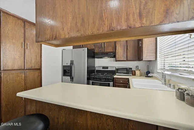 a kitchen with stainless steel appliances a refrigerator a sink a stove a microwave and island