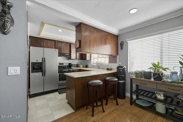 a kitchen with stainless steel appliances a stove a sink a refrigerator white cabinets and wooden floor