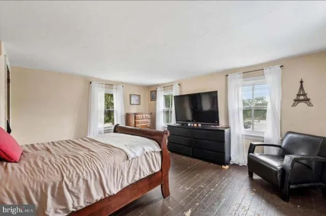 a living room with furniture and a wooden floor next to a window