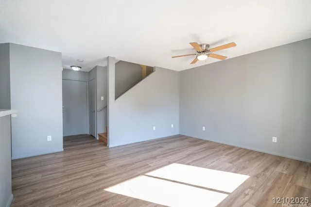 an empty room with wooden floor and ceiling fan