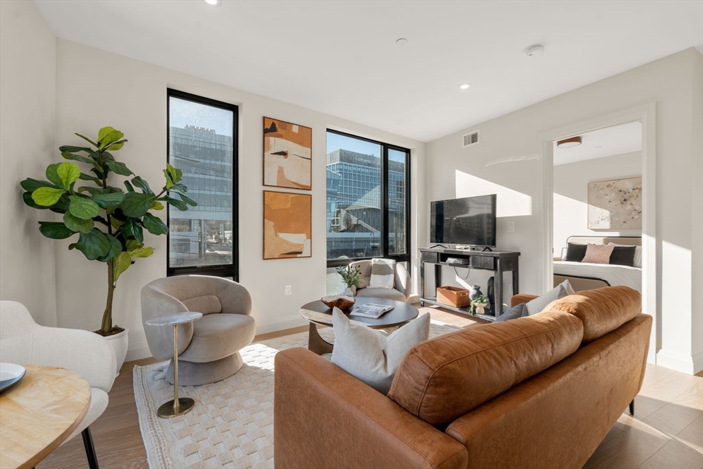 100 Lincoln Street, Unit 403 Boston, MA 02135 - Photo 8 of 23 a living room with furniture a large window and a flat screen tv