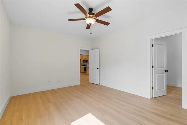 an empty room with wooden floor and ceiling fan