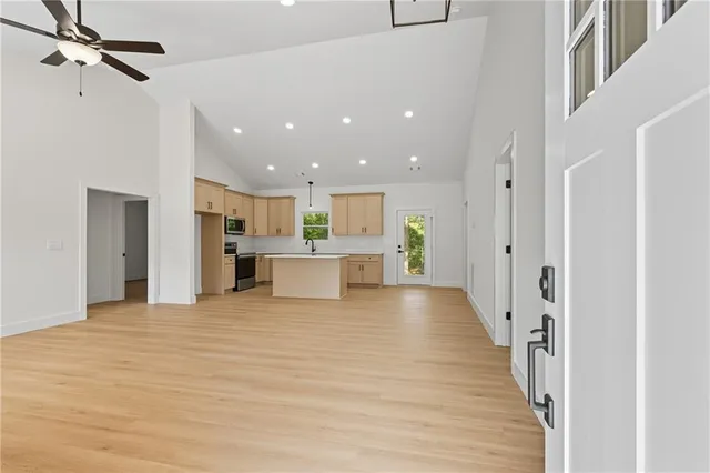 a view of a kitchen with kitchen island a sink wooden floor and stainless steel appliances