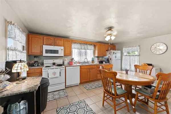 a kitchen with stainless steel appliances kitchen island granite countertop a table chairs and a refrigerator