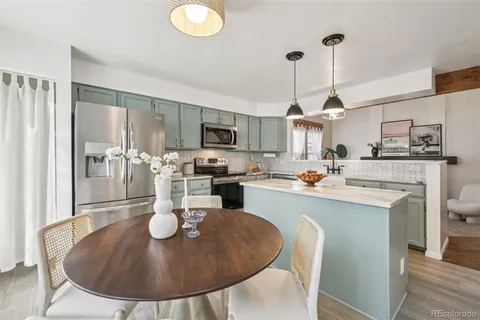 a kitchen with stainless steel appliances granite countertop a sink a stove a dining table and chairs