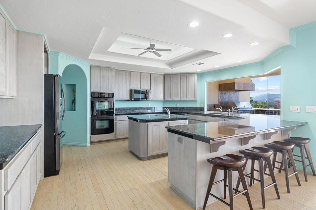 1402 Vista De Lomas Bonsall, CA 92003 - Photo 15 of 56 an open kitchen with kitchen island white cabinets and stainless steel appliances
