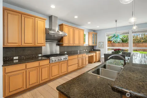 a kitchen with granite countertop a stove a sink a counter space and cabinets