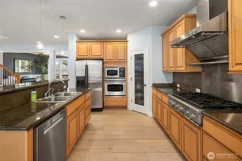 a kitchen with stainless steel appliances granite countertop a sink stove and refrigerator