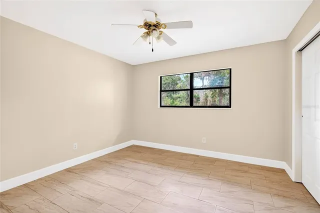 an empty room with windows and chandelier fan
