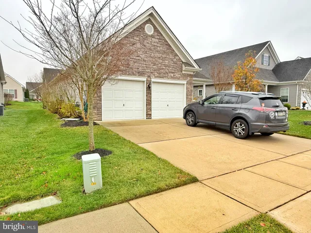 a car parked in front of a house next to a yard