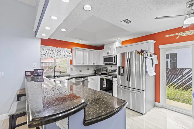 a kitchen with stainless steel appliances granite countertop a sink stove and refrigerator