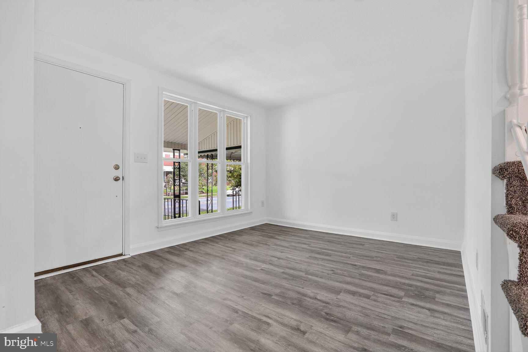 8258 Kavanagh Road Baltimore, MD 21222 - Photo 3 of 19 a view of an empty room with wooden floor and a window